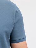 Close-up van de schouder en mouw van een blauw poloshirt met textuur.