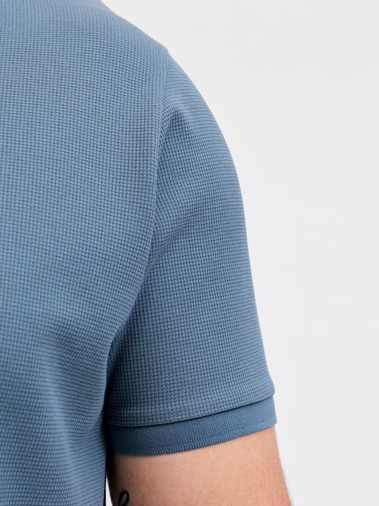 Close-up van de schouder en mouw van een blauw poloshirt met textuur.