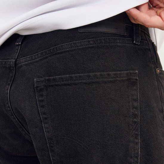 Close-up van de achterkant van een zwarte denim jeans met merklabel.