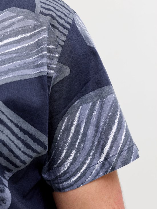 Close-up van de mouw van een blauw overhemd met abstracte grijze en witte bladprint.