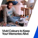 Vrouw met trui zit op vloerkleed en bekijkt foto's. Tekst: 'Vivid Colours'.