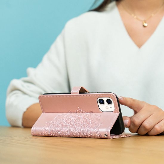 Een rosé gouden telefoonhoesje met mandela-reliëf, gebruikt als standaard voor de telefoon.