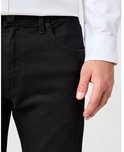 Zwarte jeans, close-up van de voorkant met zakken en een knoop.