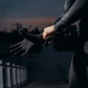 Persoon trekt zwarte sporthandschoen aan met antislip grip.