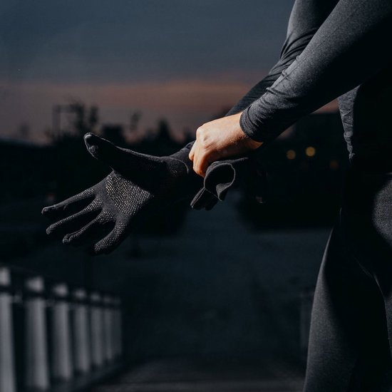 Persoon trekt zwarte sporthandschoen aan met antislip grip.
