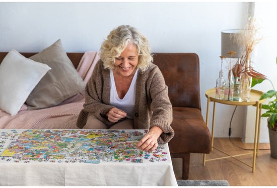 Een lachende vrouw met grijs haar, gekleed in een bruine vest, maakt een puzzel van 3000 stukjes met een museumthema.