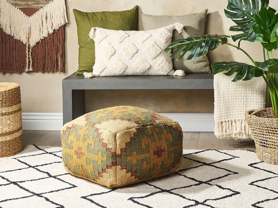 Een lichtgroene poef met geometrisch patroon staat op een vloerkleed in een woonkamer.