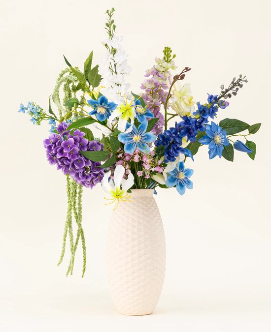 Boeket met paarse, blauwe en witte bloemen, met hangende groene bloemen, in een getextureerde beige vaas.