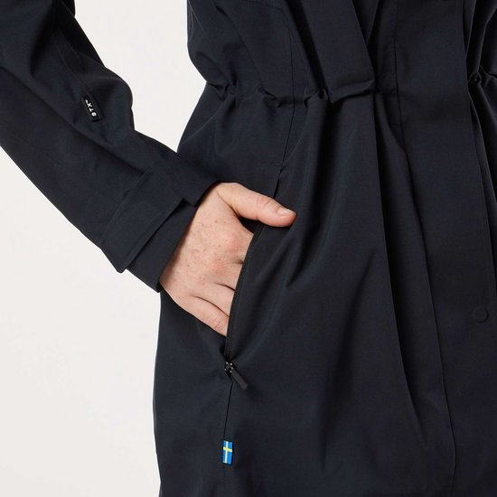 Détail de la poche d'un manteau noir avec fermeture éclair et un petit drapeau suédois.