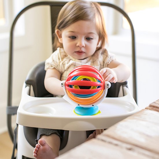 Baby in staelen kinderstoel speelt met een kleurrijke Baby Einstein sticky spinner met rode, oranje, blauwe en gele ringen.