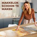 Une femme nettoie un chemin de table en vinyle imprimé marbre gris, blanc et doré, avec le texte 'Facile à nettoyer'.