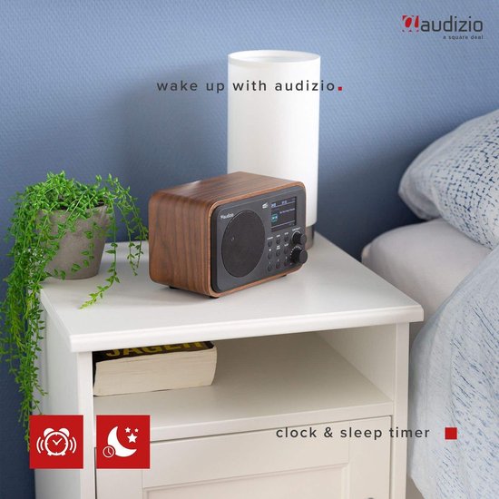 DAB radio met houtlook op een nachtkastje naast een lamp en plant.