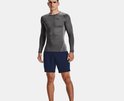 Man in grijs Under Armour sportshirt met zwarte logo's en blauwe shorts.