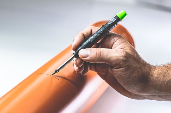 Hand met Pica-Dry markeerstift die een lijn tekent op een oranje buis.