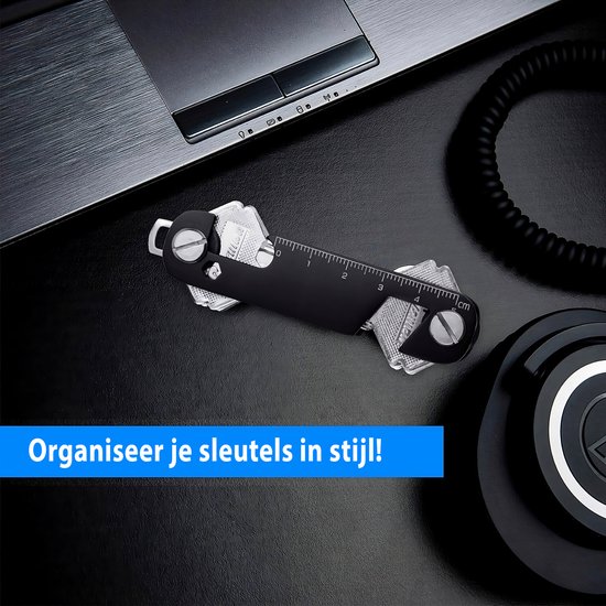 Zwarte sleutelhouder met 6 sleutels op een bureau naast een laptop en koptelefoon.