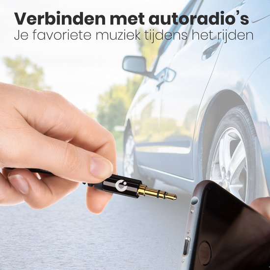 Hand houdt gouden 3,5 mm jackplug in van zwarte AUX-kabel, naast smartphone in auto.