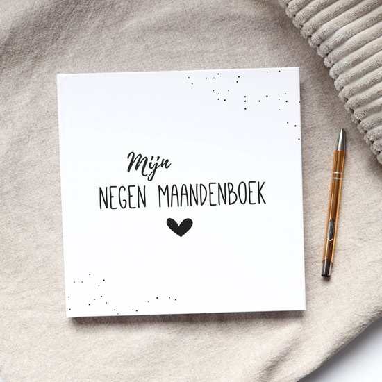 Zwart-wit baby dagboek 'Mijn negen maandenboek' met hartje, op een linnen ondergrond met pen.