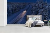 Behang - Fotobehang Een auto rijdt over een besneeuwde landweg van Lapland - Breedte 465 cm x hoogte 260 cm