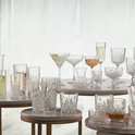 Une collection de verres et carafes en cristal de différentes tailles et formes, certains remplis de boissons.