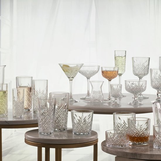 Une collection de verres et carafes en cristal de différentes tailles et formes, certains remplis de boissons.