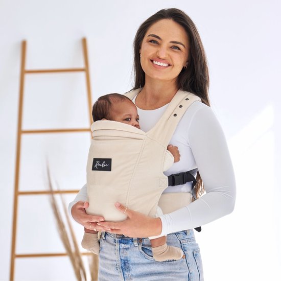 Vrouw met baby in een beige corduroy draagzak.