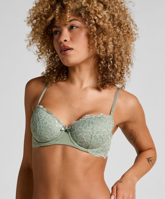 Model met een lichtgroene kanten beugel bh, versierd met strikje en witte rand.