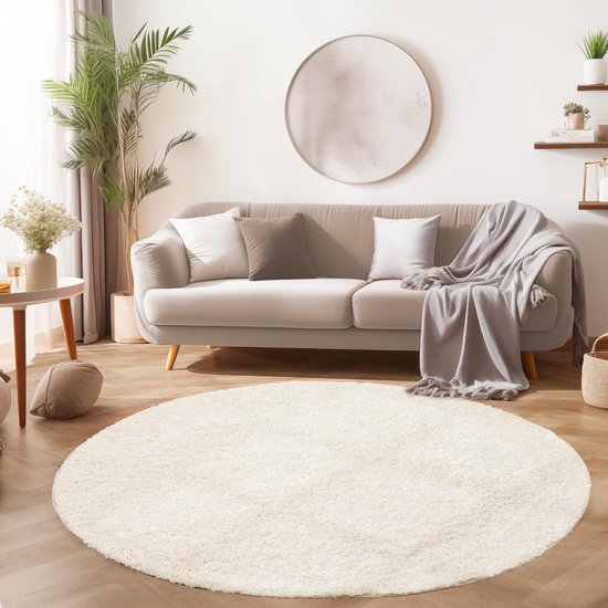 Un tapis rond crème à poils longs dans un salon moderne avec un canapé gris.