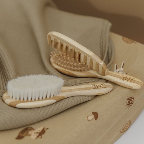 Zandkleurige aankleedkussenhoes met bosdierenprint en een babyverzorgingsset.