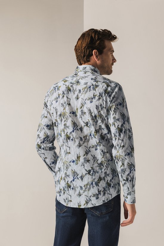 Man van achteren gezien in een lichtgrijs overhemd met botanische print en spijkerbroek.