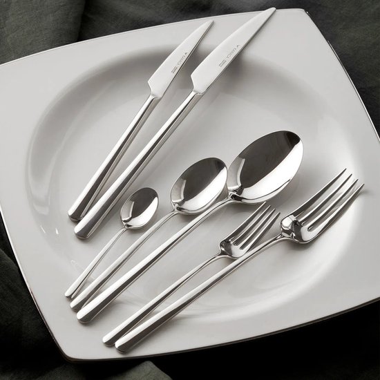 Un ensemble de couverts argentés brillants sur un plat blanc carré: deux couteaux, trois cuillères et deux fourchettes, avec des manches fins.