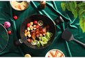 Une poêle noire avec des saucisses grillées, des légumes et du citron.
