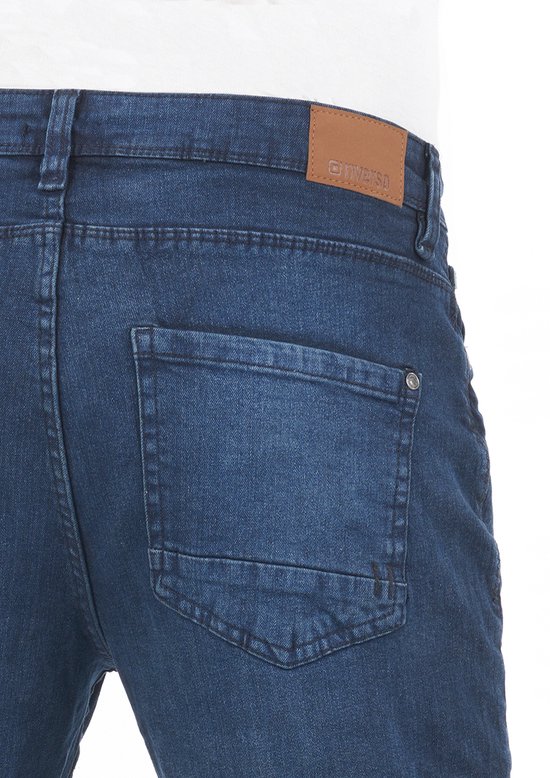 Gedetailleerde foto van de achterkant van een donkerblauwe jeans met twee zakken en een bruin Riverso label op de tailleband.