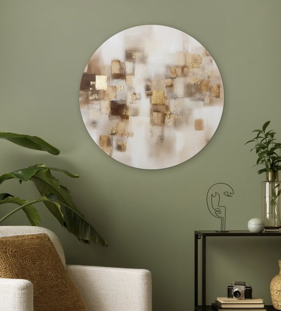Ronde muurcirkel met abstracte bruine en gouden vierkanten op een lichte achtergrond, hangend aan een muisgrijze muur naast een witte bank.
