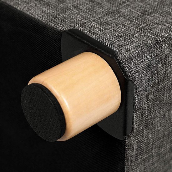 Detail van een houten pootje met zwarte bescherming onderaan de grijze stoffen poef.