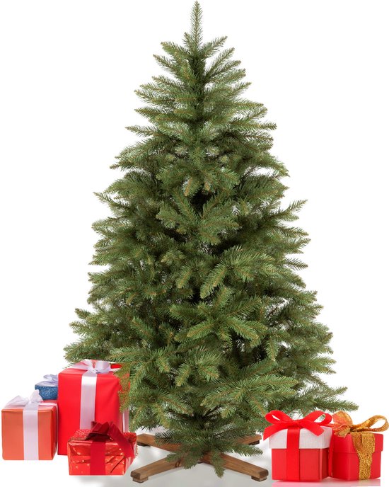 Een groene kunstkerstboom met houten standaard, omringd door rode en gouden cadeaus.