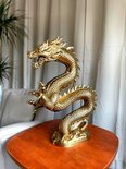 Gouden drakenbeeld met een kronkelende staart, schubben en een gedetailleerde kop, staand op een houten tafel.