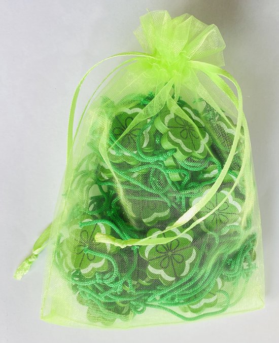 Een lichtgroen gaas zakje met daarin groene klavertje vier hangers met koordjes.