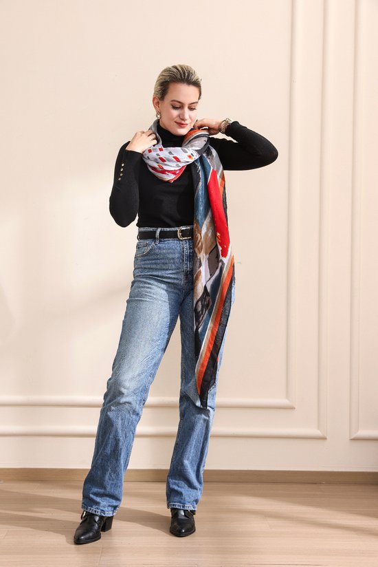 Mannequin portant une écharpe à imprimé abstrait rouge, bleu, orange et beige sur un col roulé noir et un jean.
