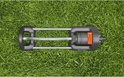 Zwenksproeier met grijze en oranje delen, liggend op gras.