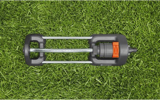 Zwenksproeier met grijze en oranje delen, liggend op gras.