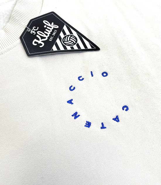 Off-white sweater met blauwe tekst in cirkelvorm en zwart FC Kluif label.