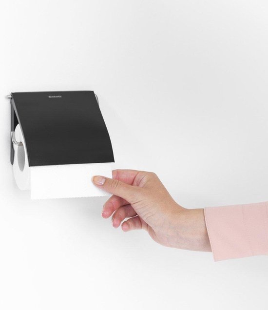 Porte-rouleau toilette noir avec rabat, une main tire le papier toilette.