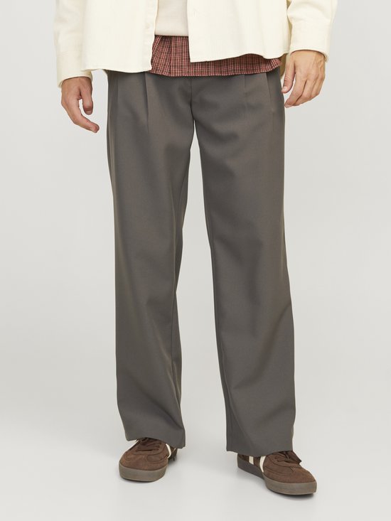 Donkergrijze broek met wijde pijpen, gedragen door een man met een wit vest en bruine schoenen.