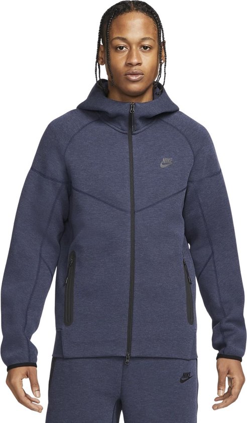 Model met donkerblauw Nike Tech Fleece vest met capuchon en rits.