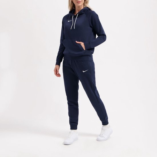 Donkerblauwe Nike hoodie en joggingbroek gedragen door een model, met witte Nike logo's.