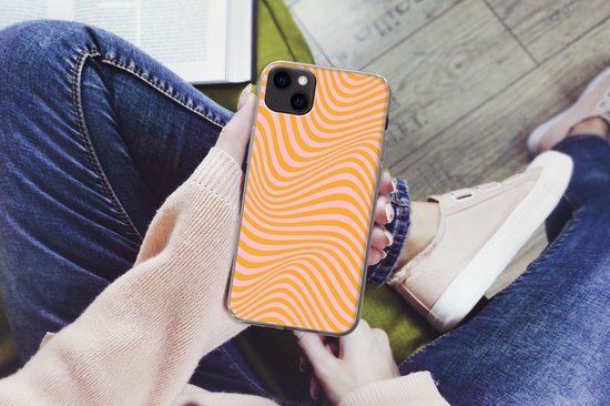 Mains tenant une coque pour iPhone 13 mini à motif ondulé orange et rose.
