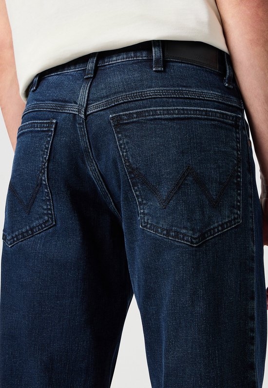 Close-up van de achterkant van een donkerblauwe spijkerbroek met Wrangler logo.
