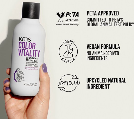 KMS Color Vitality conditioner fles met PETA Approved en Vegan logo's. Een hand met paars gelakte nagel houdt de fles vast.