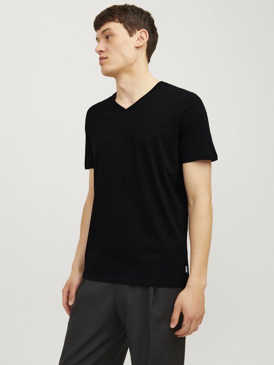 Man met zwart T-shirt met V-hals en grijs pinstreep broek, zijwaarts.