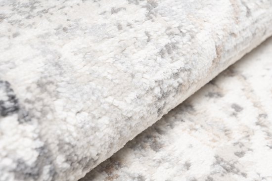 Gros plan sur la texture d'un tapis beige, avec de subtiles décolorations grises et brunes.